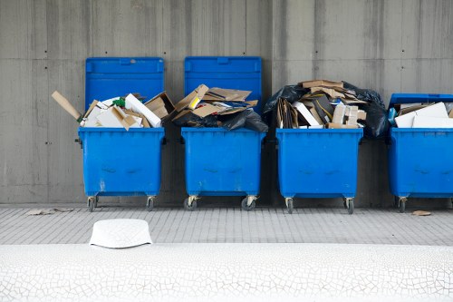 Skip hire vehicle and waste containers beside pavement